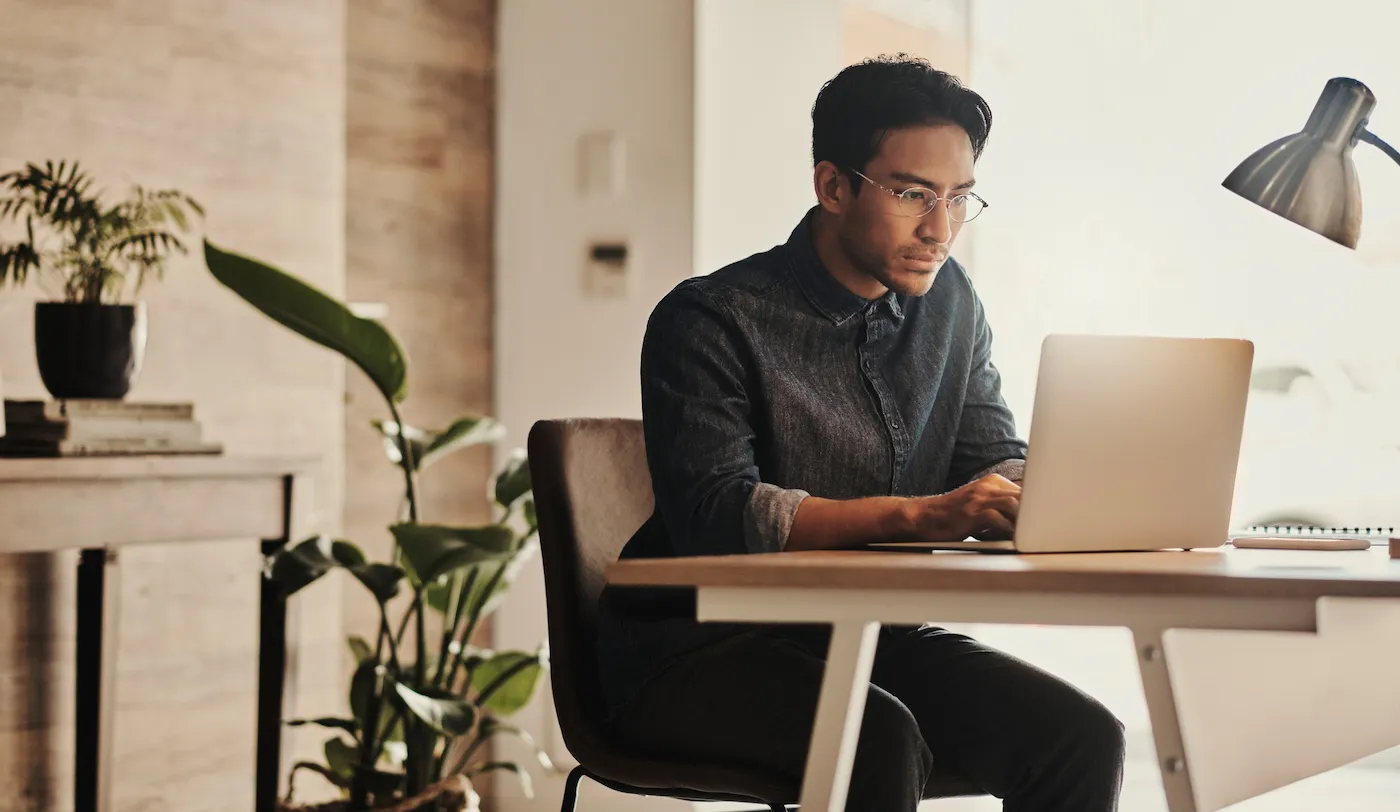 A man researching conforming and conventional loans on his laptop at a desk.