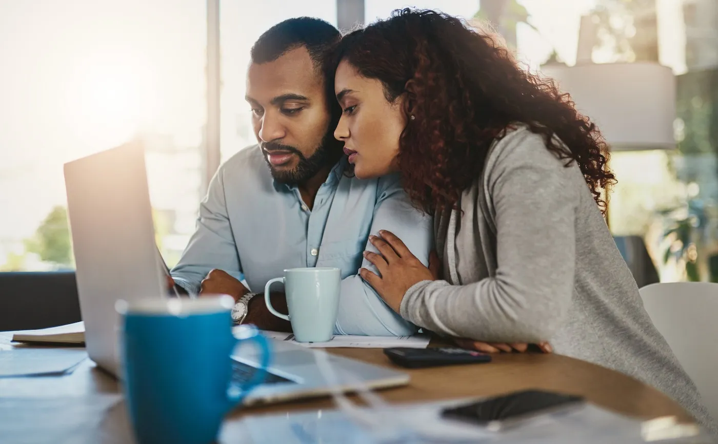 Shot of a young couple using a laptop while buying life insurance at home