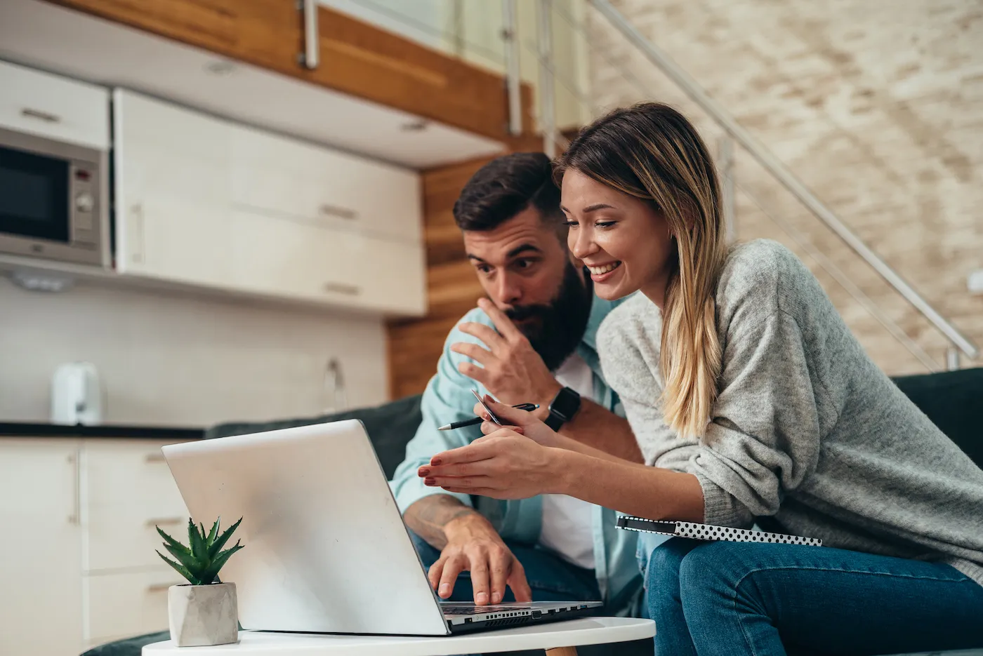 A couple working on a laptop from their couch to get a bigger tax refund.