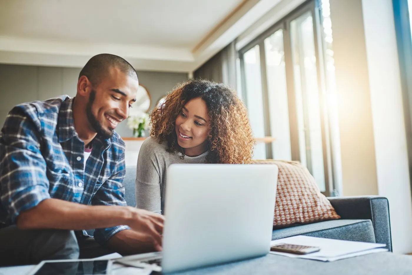 Shot of a young couple using a laptop to make an automated savings plan.