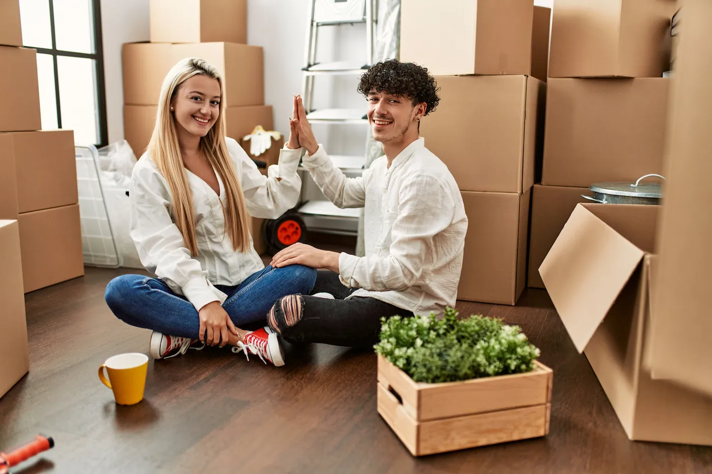 Young couple smiling happy celebrating with hands raised up at new home after getting an adjustable rate mortgage.