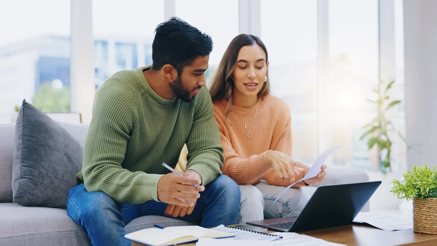 A couple on their sofa looking at finances.