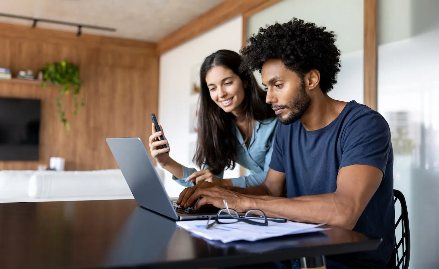 A couple at home paying bills online using a laptop.