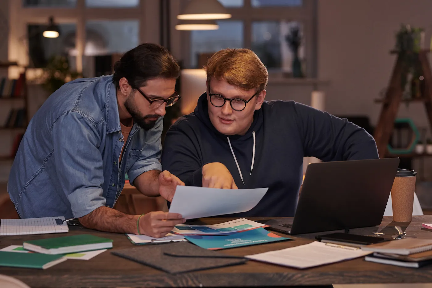 Two businessmen sitting at the table and discussing stocks, working at office