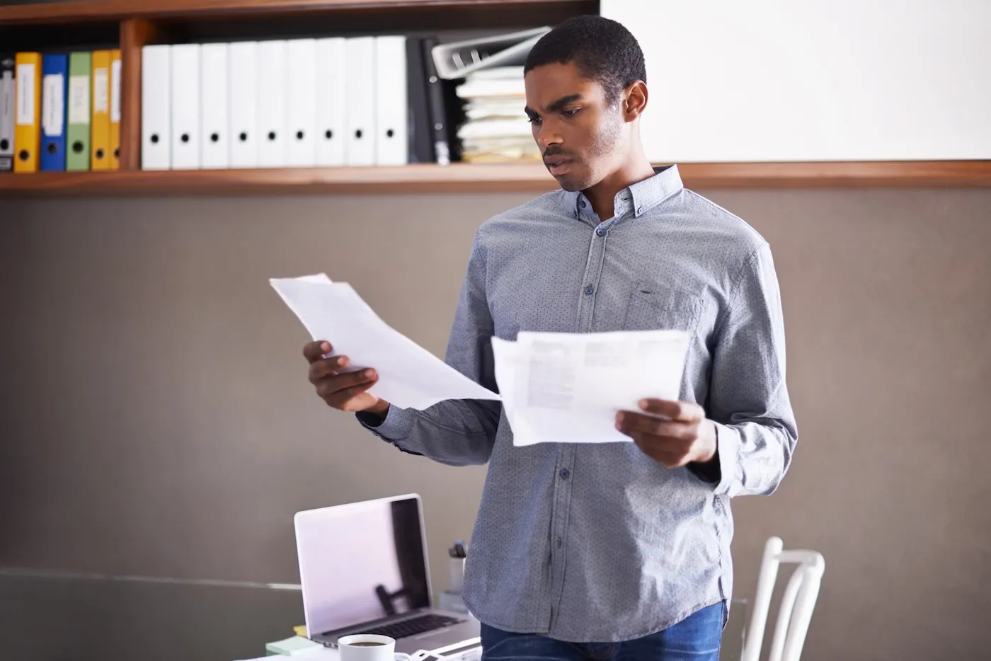 Shot of a man looking over some paperwork in his home office.