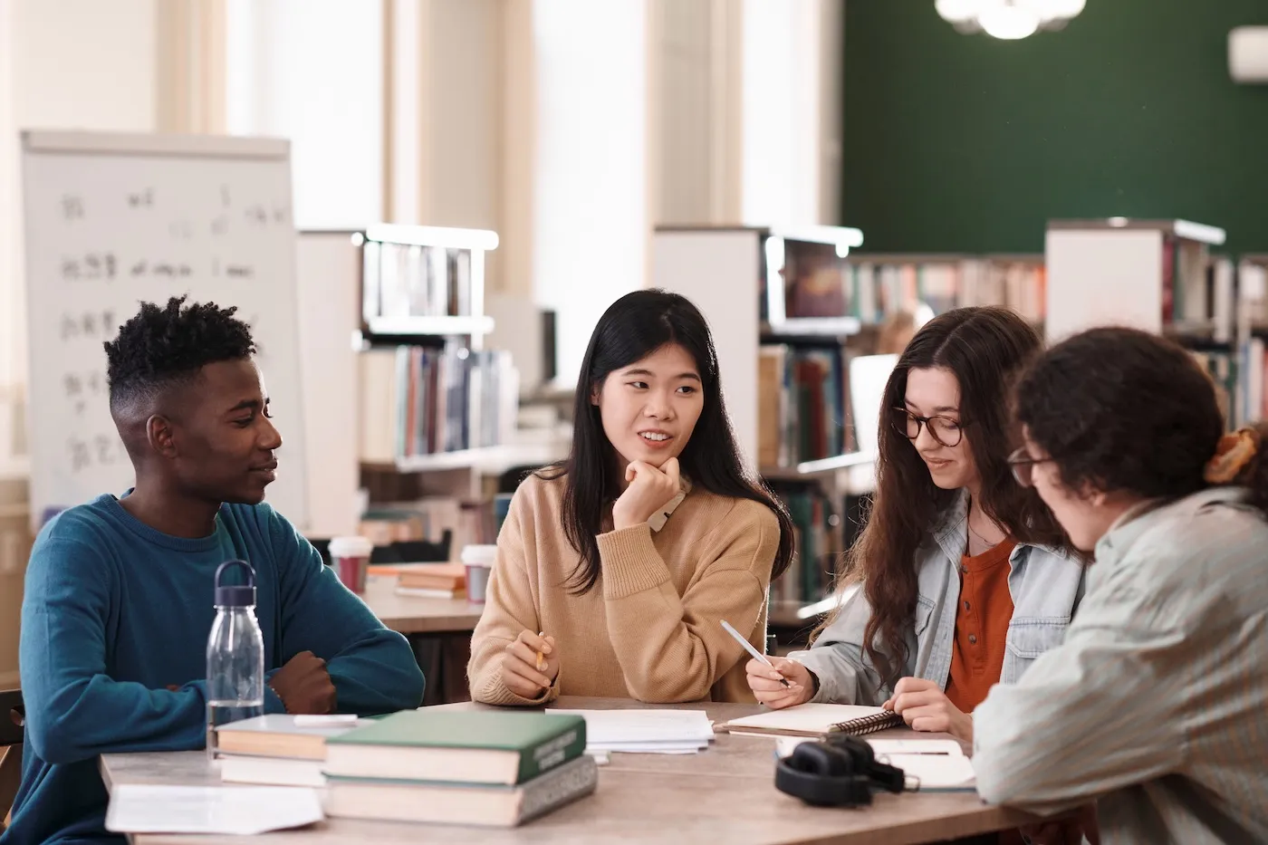 A group of students sitting at a table in their college library and studying together.