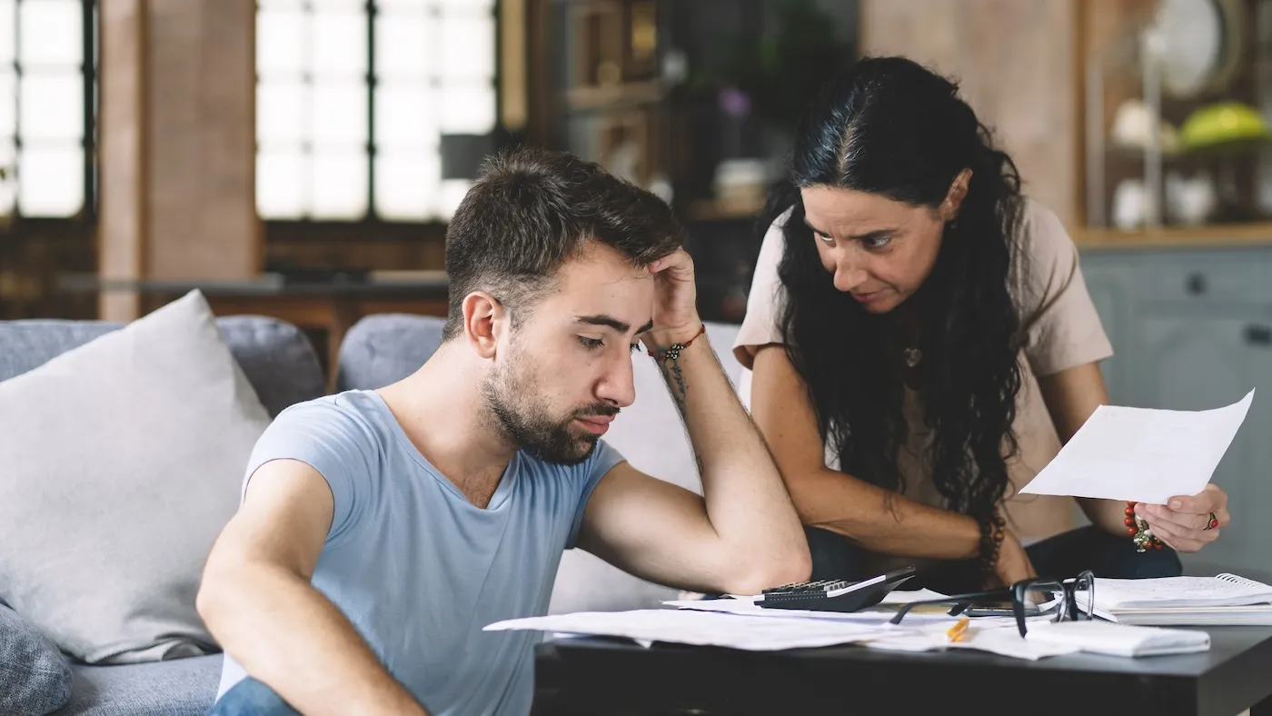 Frustrated concerned young couple calculating their overspending on budget.