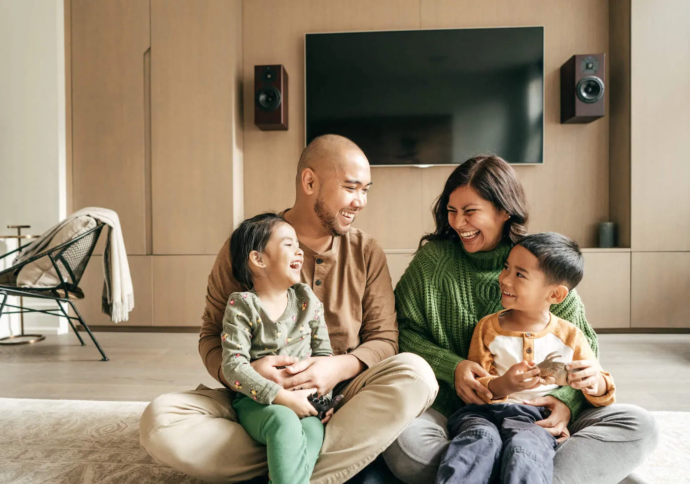 Family of four seated on the floor in their house.