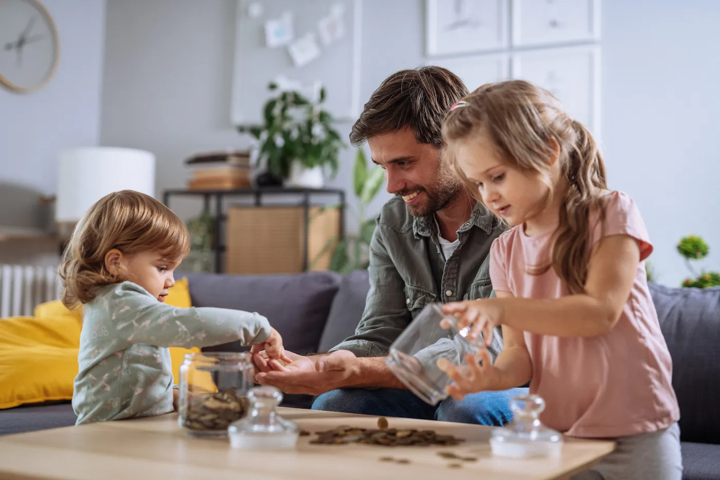 father helps young children count coins at home