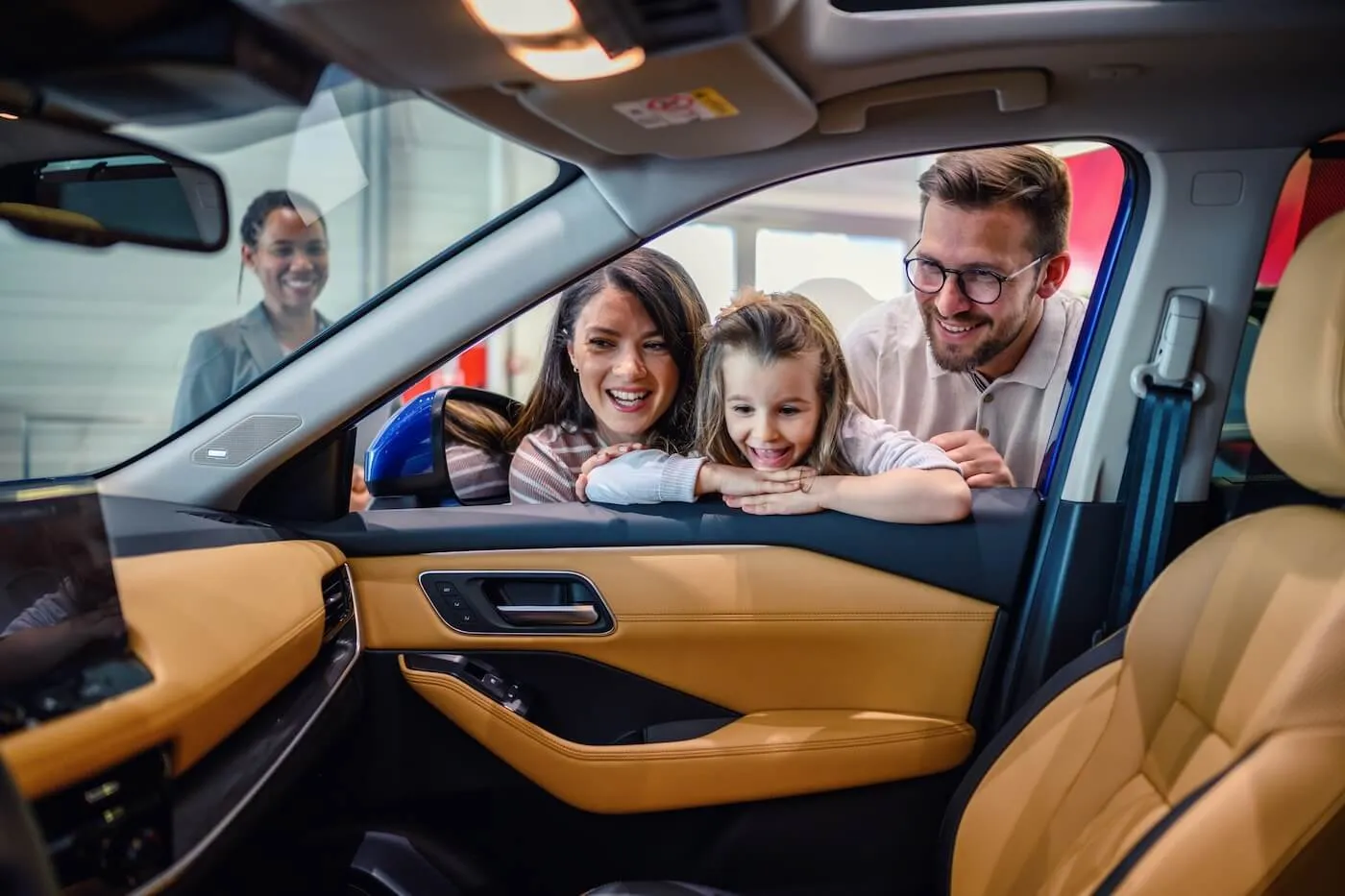 Happy family of 3 checking a new car with a female sales representative