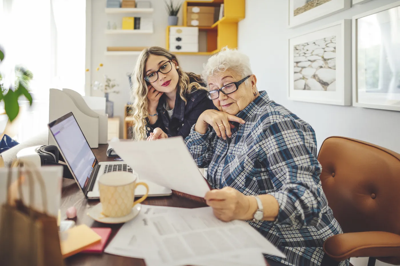 Granddaughter and grandmother sitting together at a desk reviewing finances