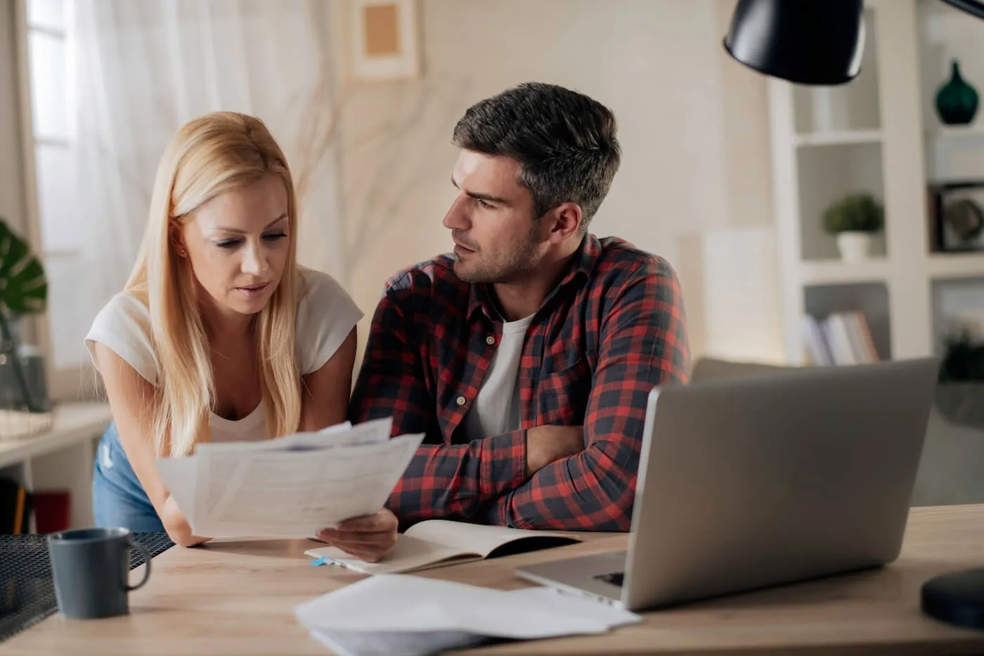 Frustrated couple reviewing their mail in the living room while using the laptop