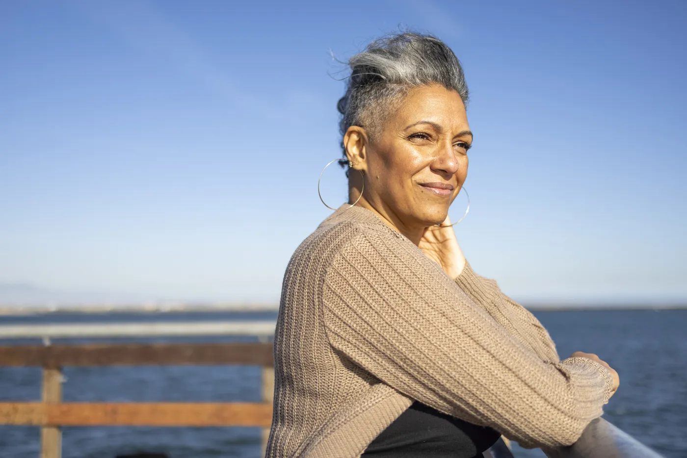 A mature woman relaxes on the pier at the beach.