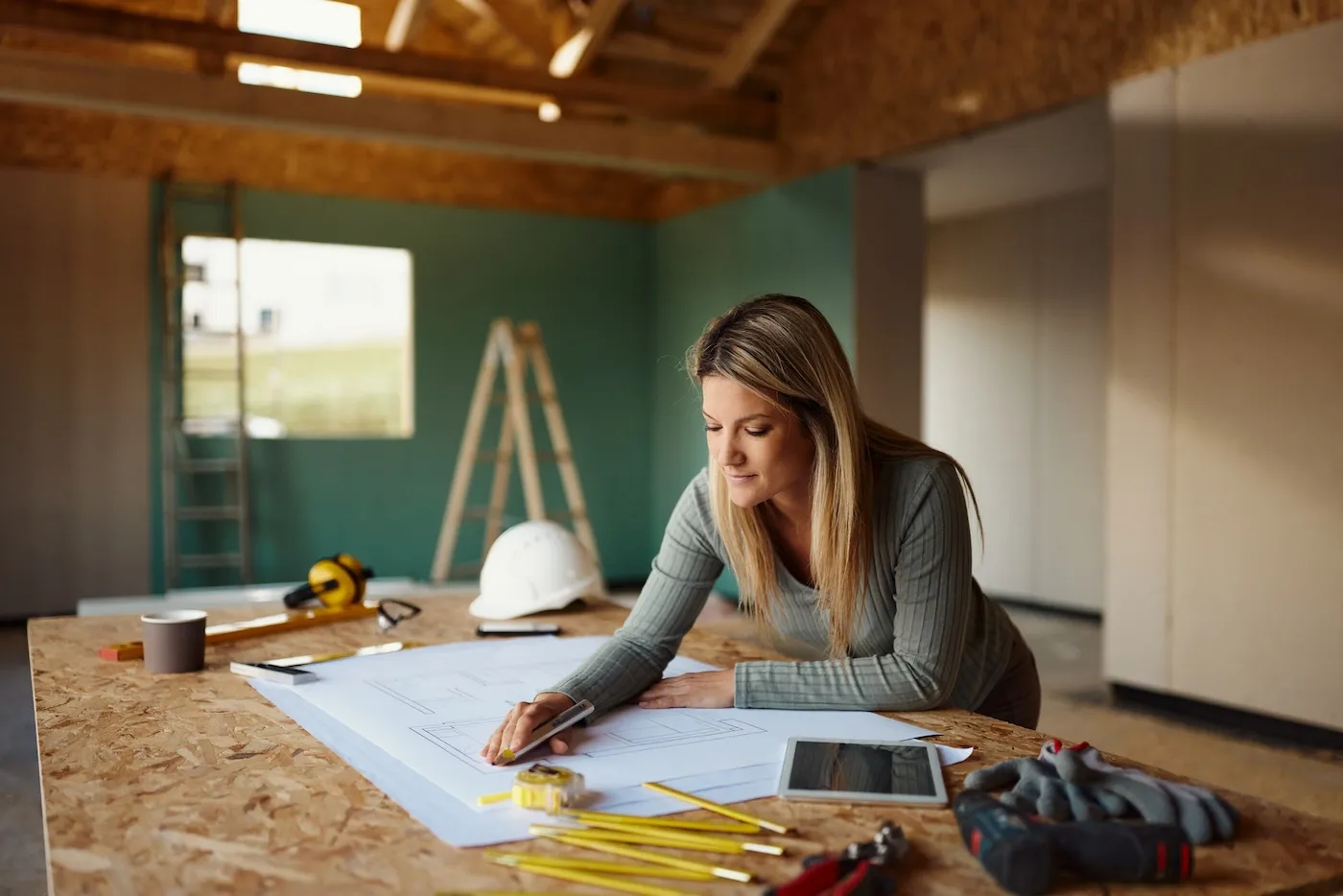 Young female inspector examining housing rebuilding plans at construction site.