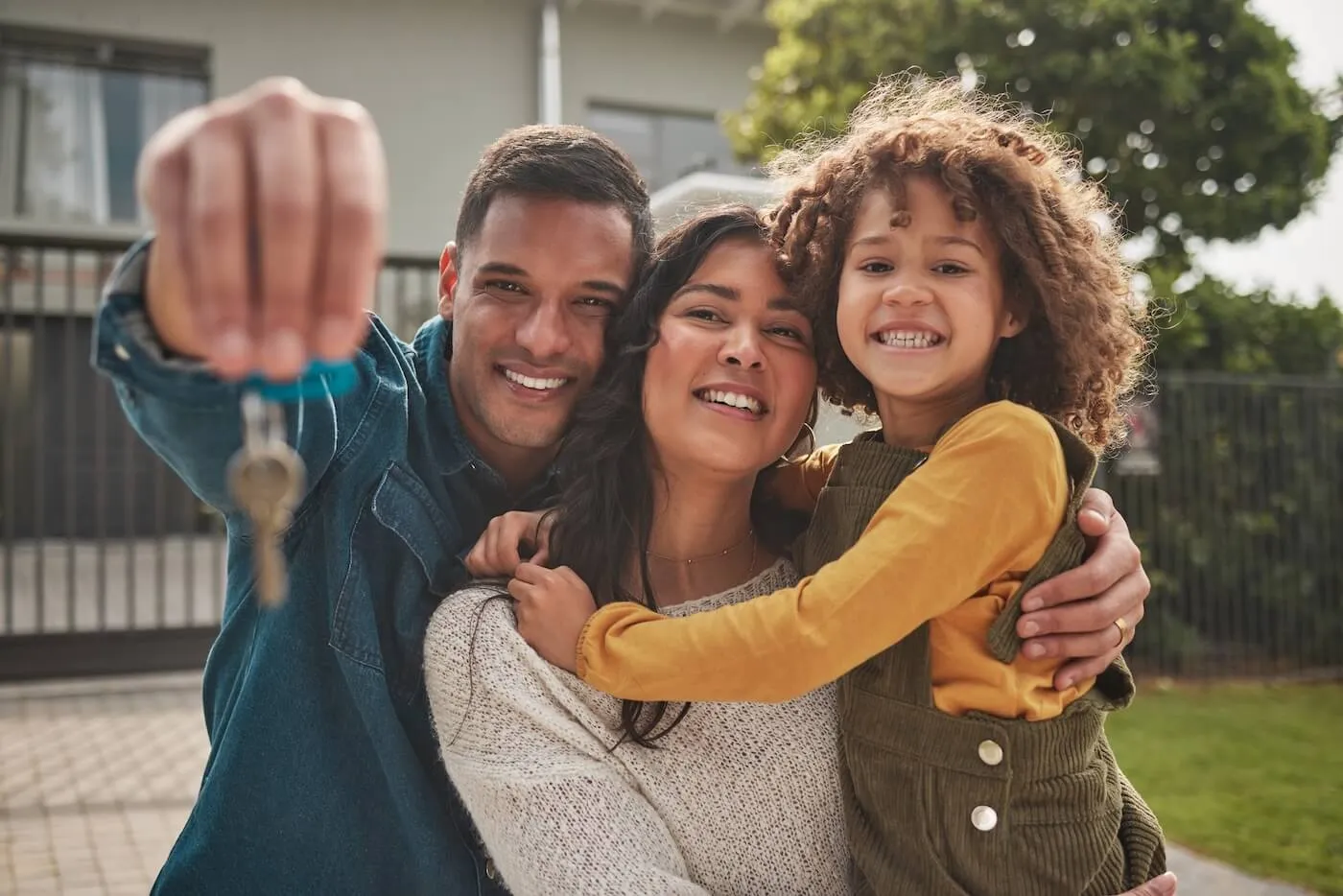 A happy family of three holding the key from their new home