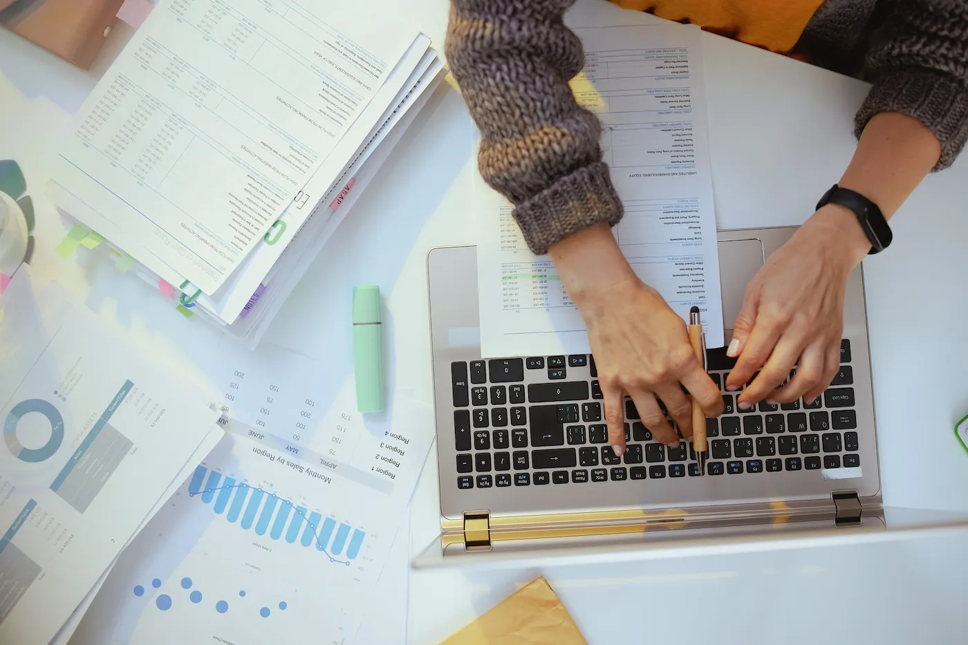 Top down shot of a woman with documents and laptop, working.