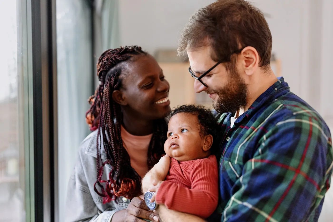 Happy parents spend time with their baby at home.