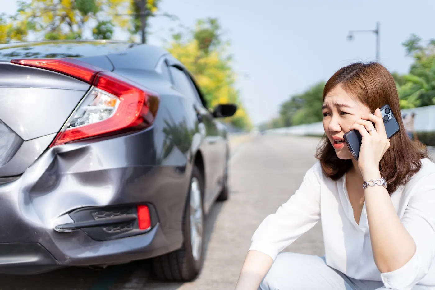 Upset woman calling her insurance after a minor car collision.