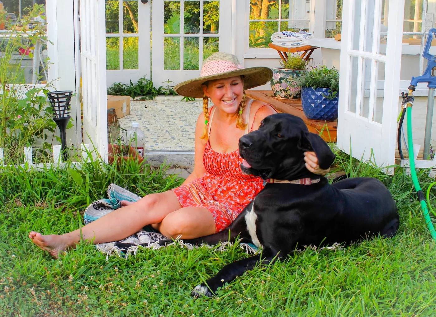 Happy and relaxed mature woman enjoying her beautiful garden with her handsome Great Dane.