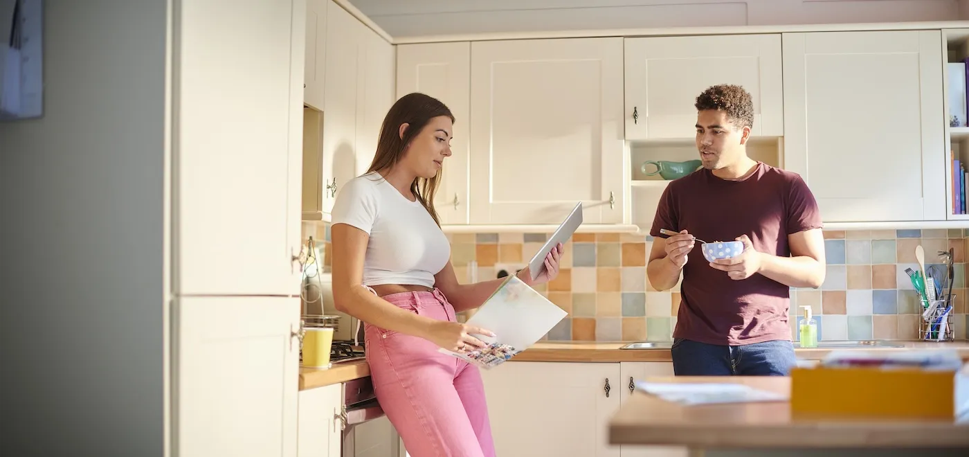 Two young homeowners checking their budget online from their kitchen.