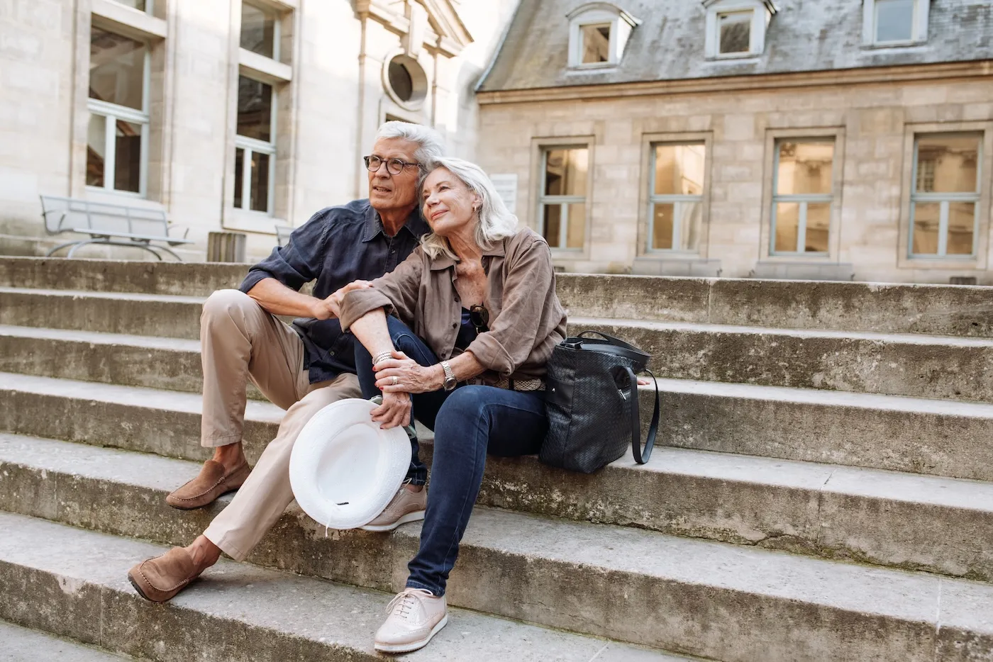 Retired husband and wife sitting on the stairs while traveling.