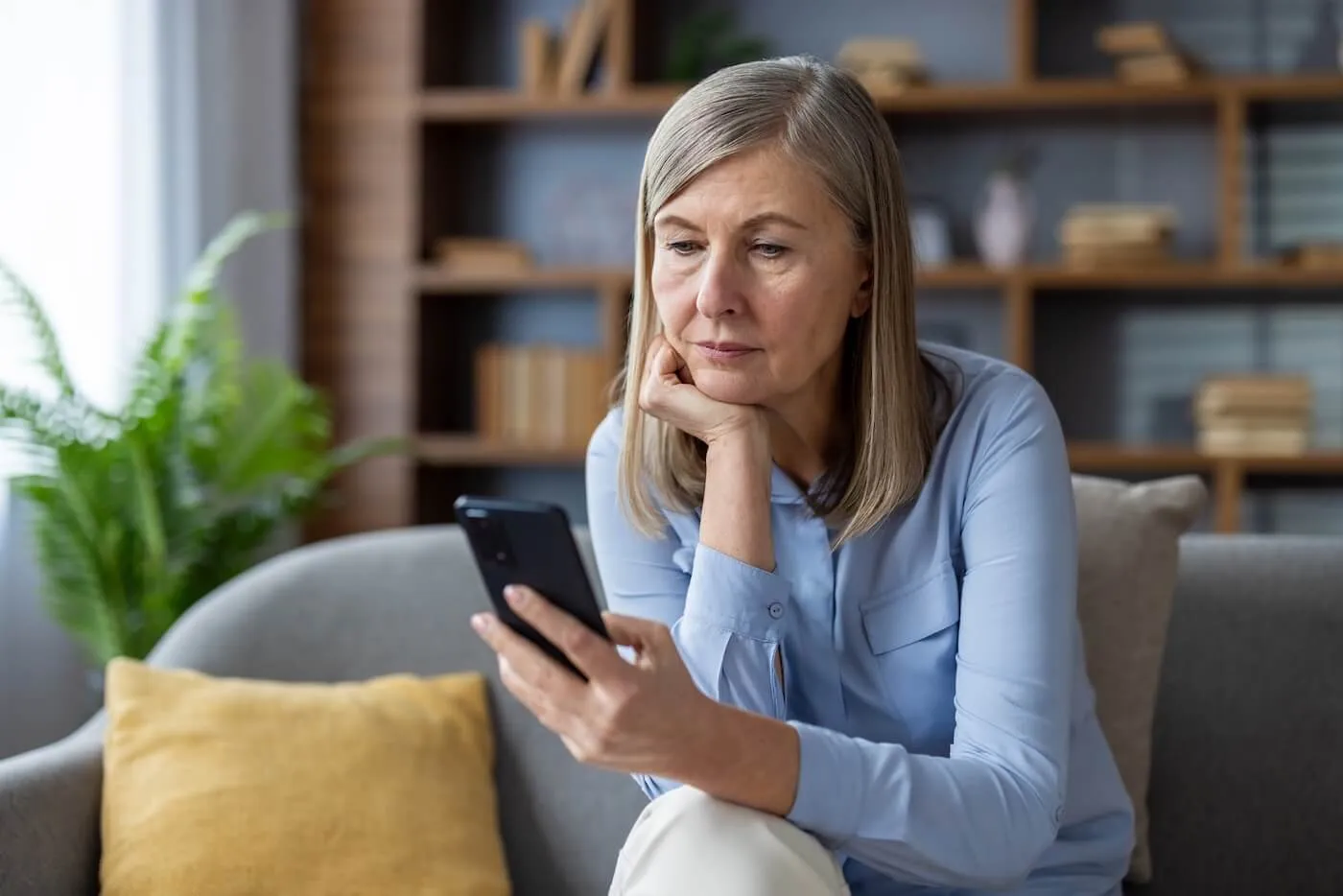 Mature woman sitting on a couch with her smartphone