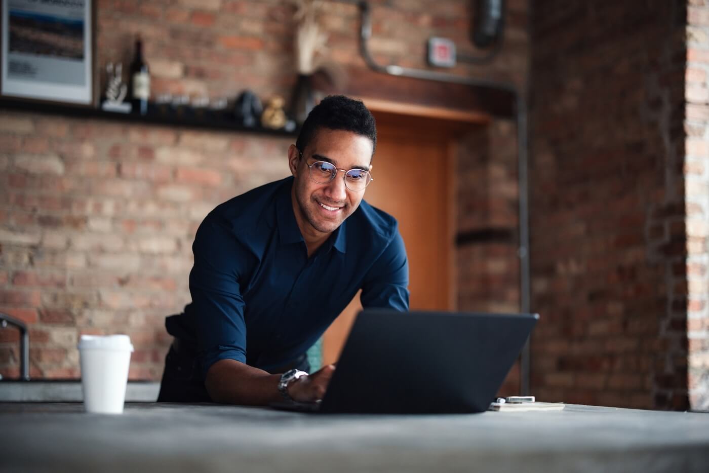 Smiling man wearing glasses using his laptop in the modern living room