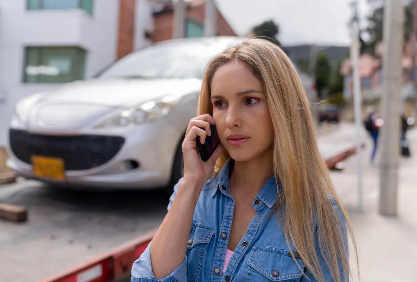 Portrait of a woman calling her car insurance while her car is being towed.