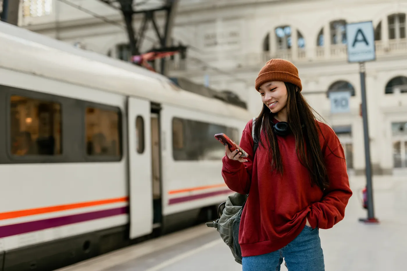 A woman standing at modern train station using her smart phone.