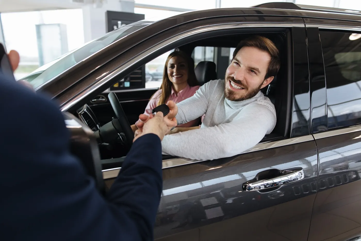 Couple receiving a new car keys from car salesperson.