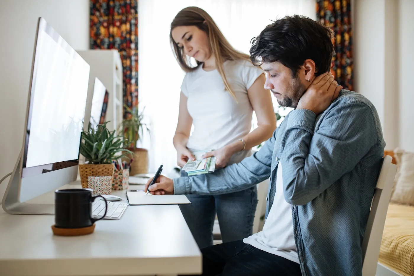 Serious young couple checking documents with using computer.