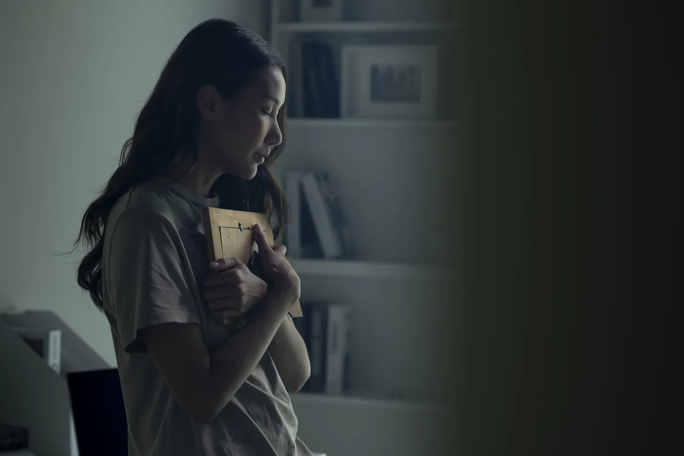 Woman feeling sad when looking at picture of lost loved one in the frame.