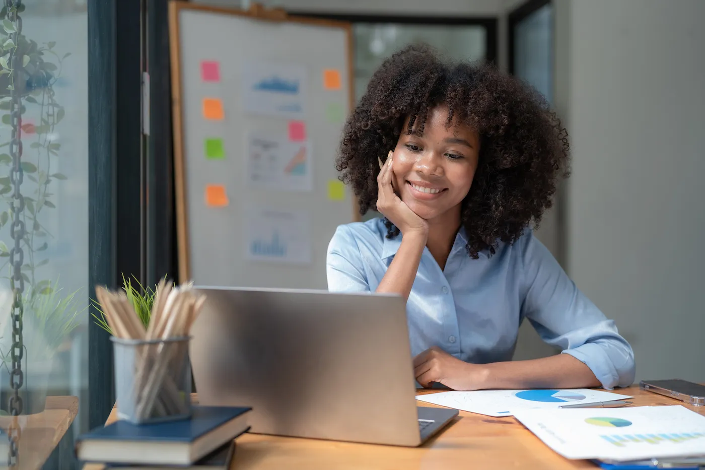 Smiling woman working on a laptop sitting at her desk in a modern office.