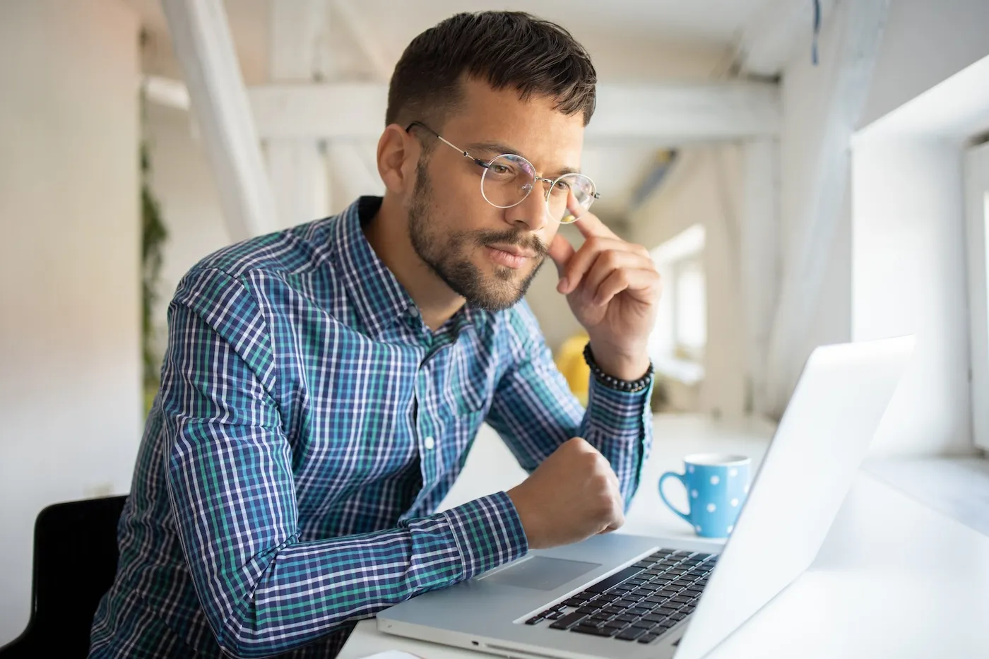 Young man in glasses using his laptop