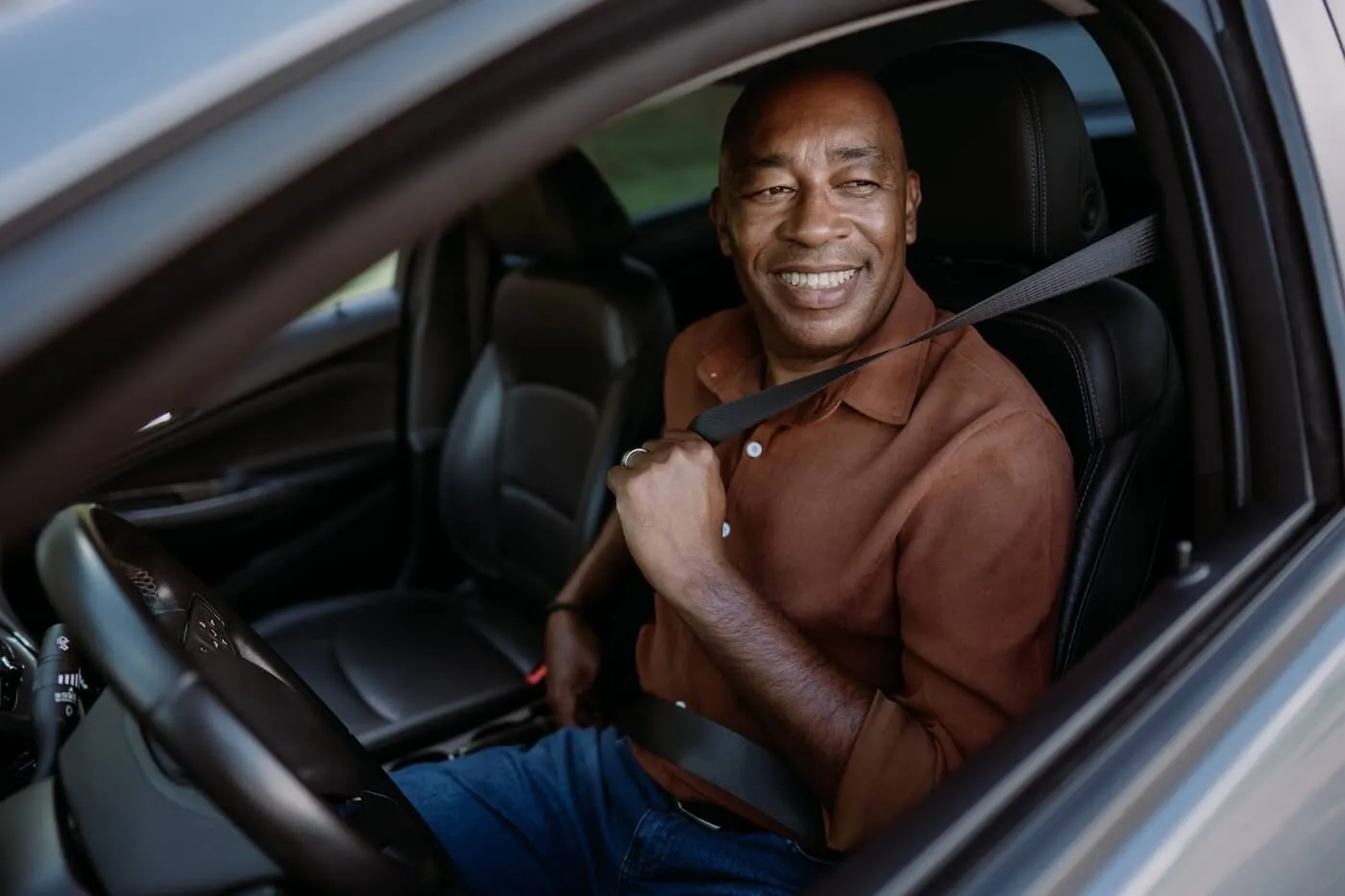 Smiling mature man fastens the seatbelt on a driver's seat