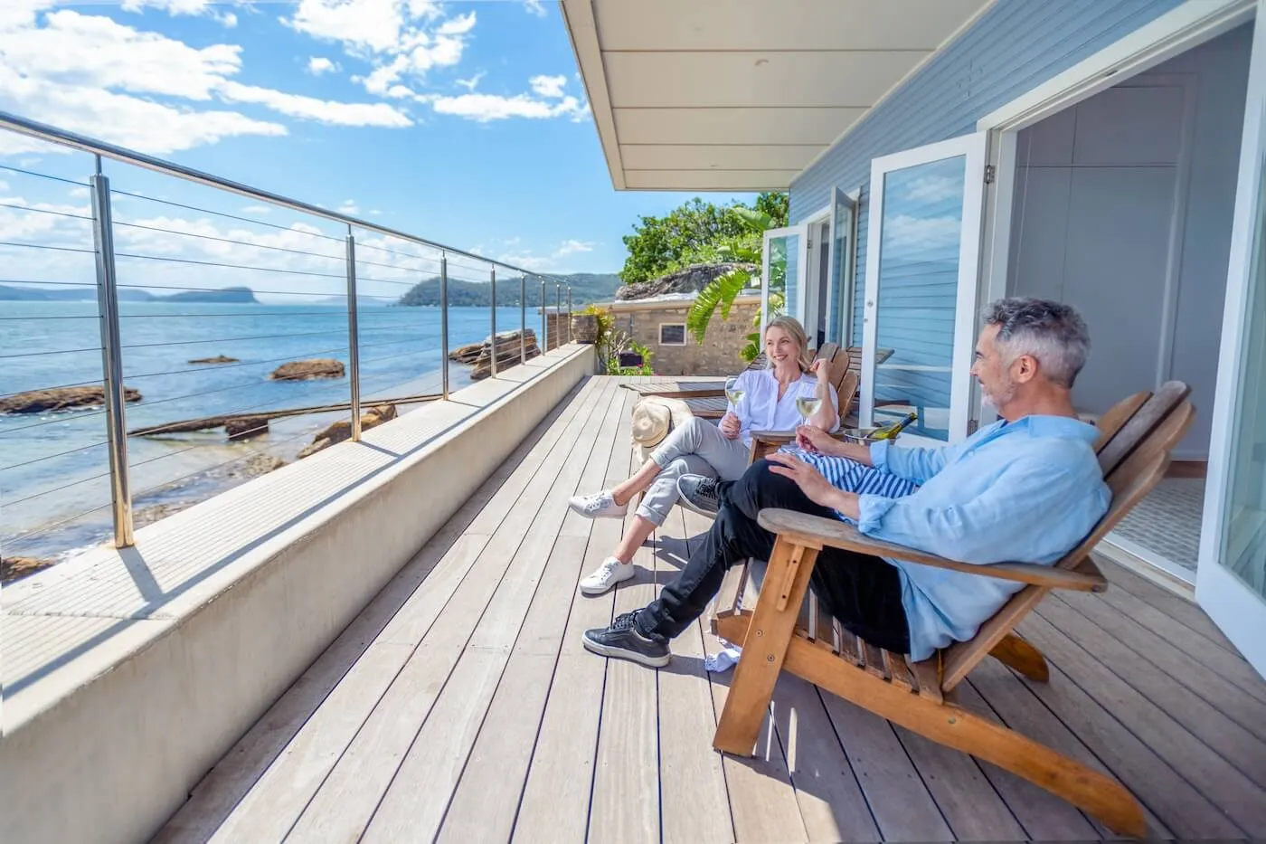 Happy mature couple enjoying a glass of wine on the sea view balcony in a vacation rental