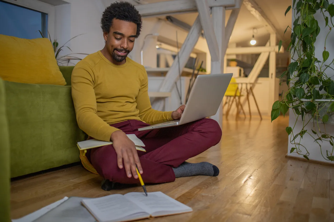 Shot of a young man sitting on the floor, working from home on his finances