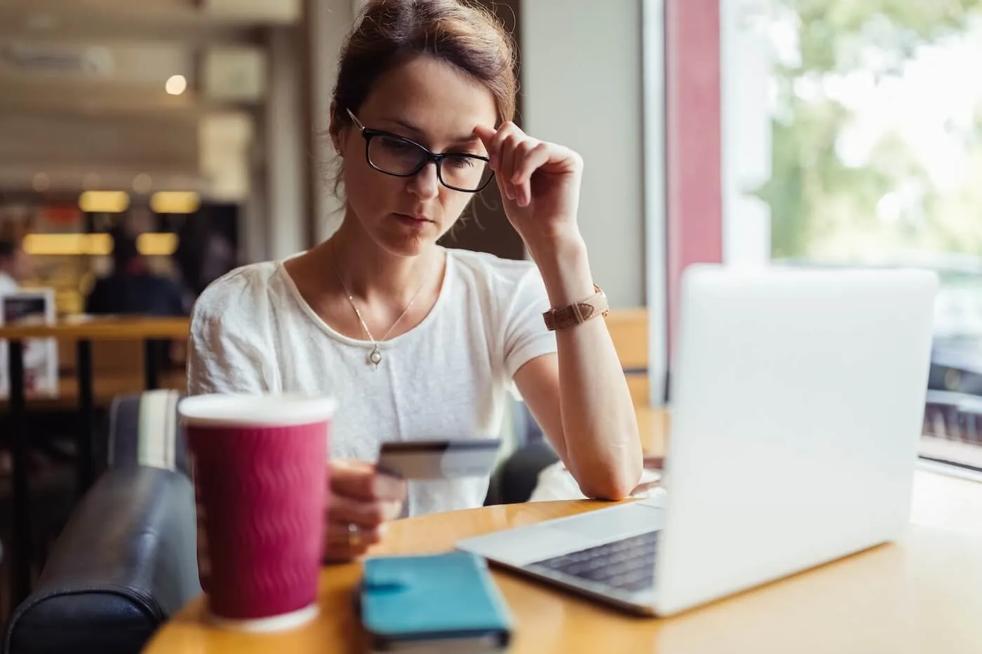 Concerned woman holding a credit card while making a payment on her laptop