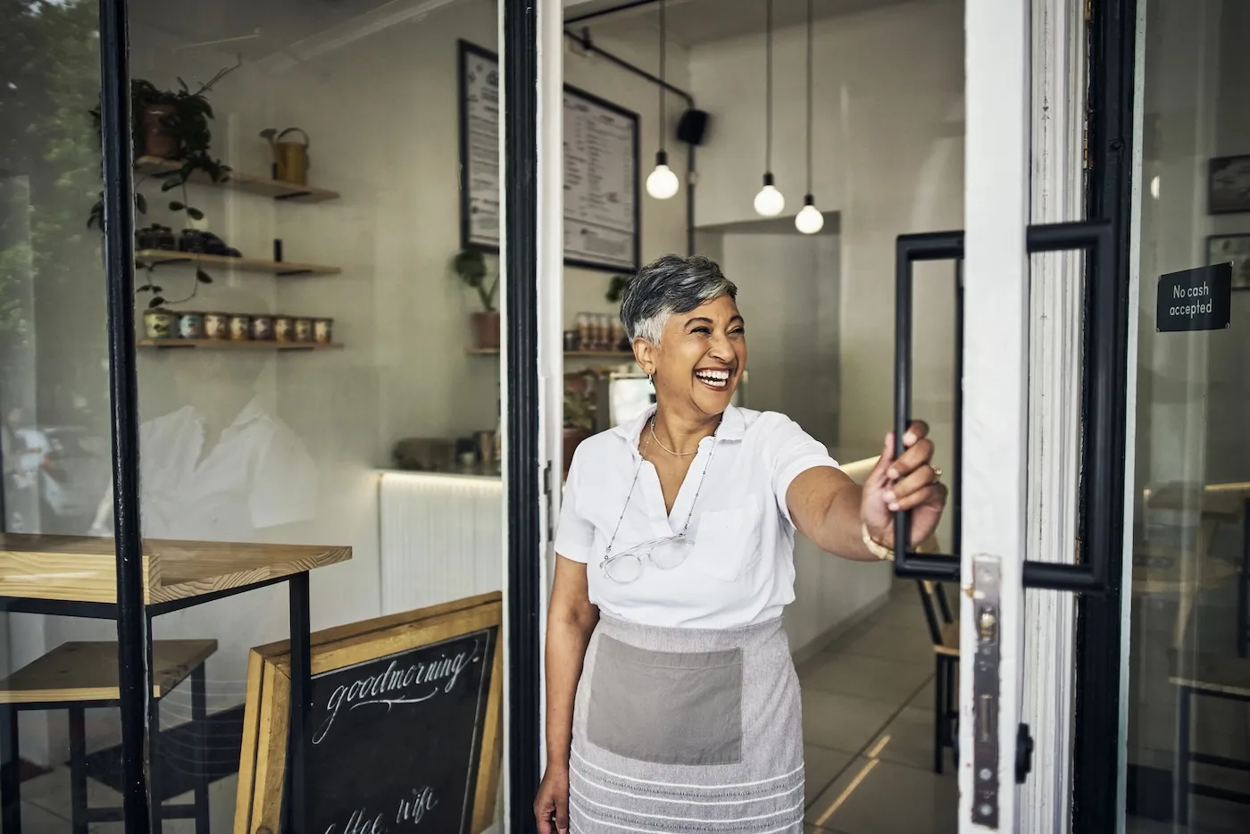 Small business owner standing in a coffee shop front door.