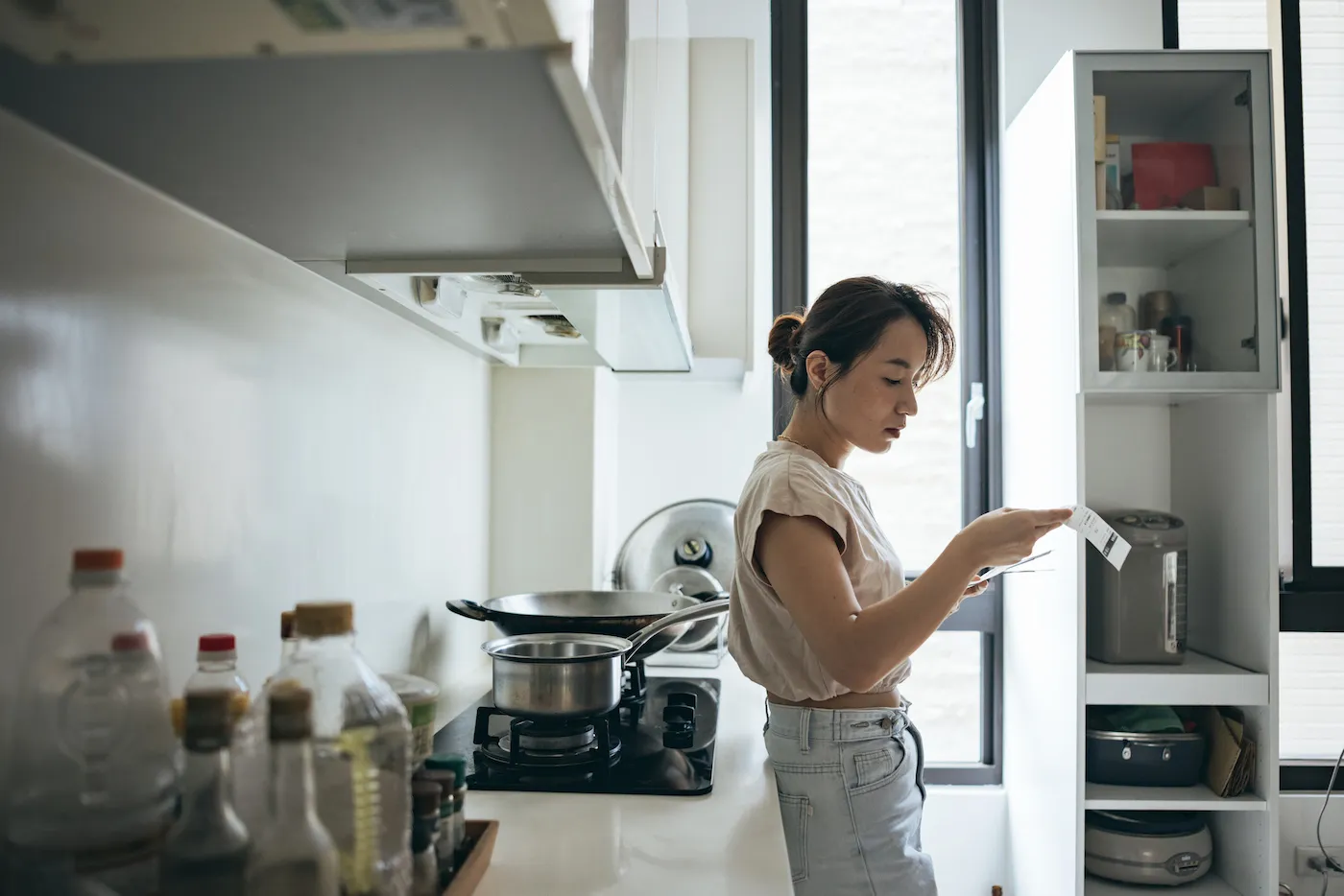 Woman holding paper various expense bills and plans for personal finances at her home.