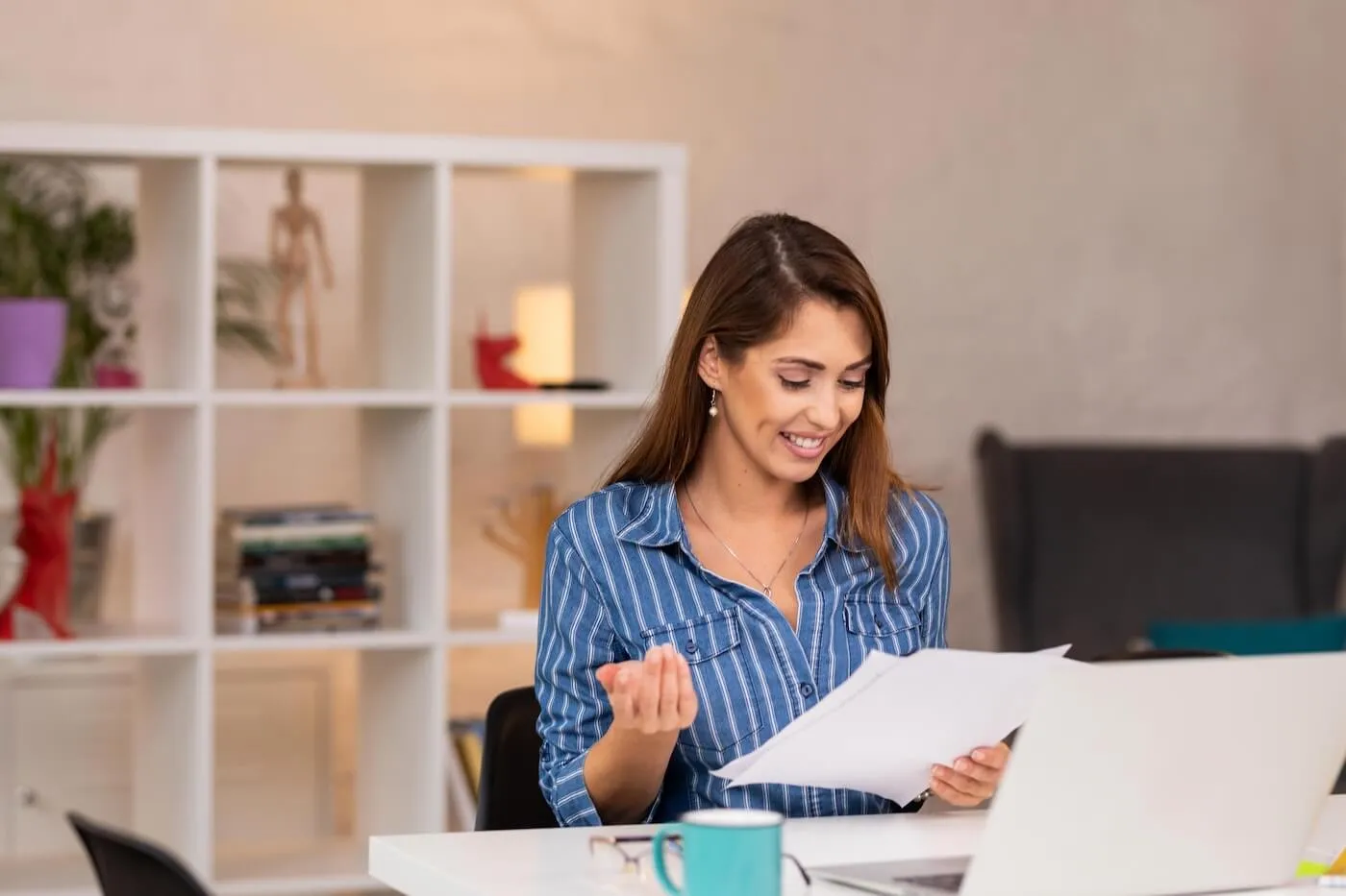 Woman reviewing printouts while making a budget spreadsheet on her laptop