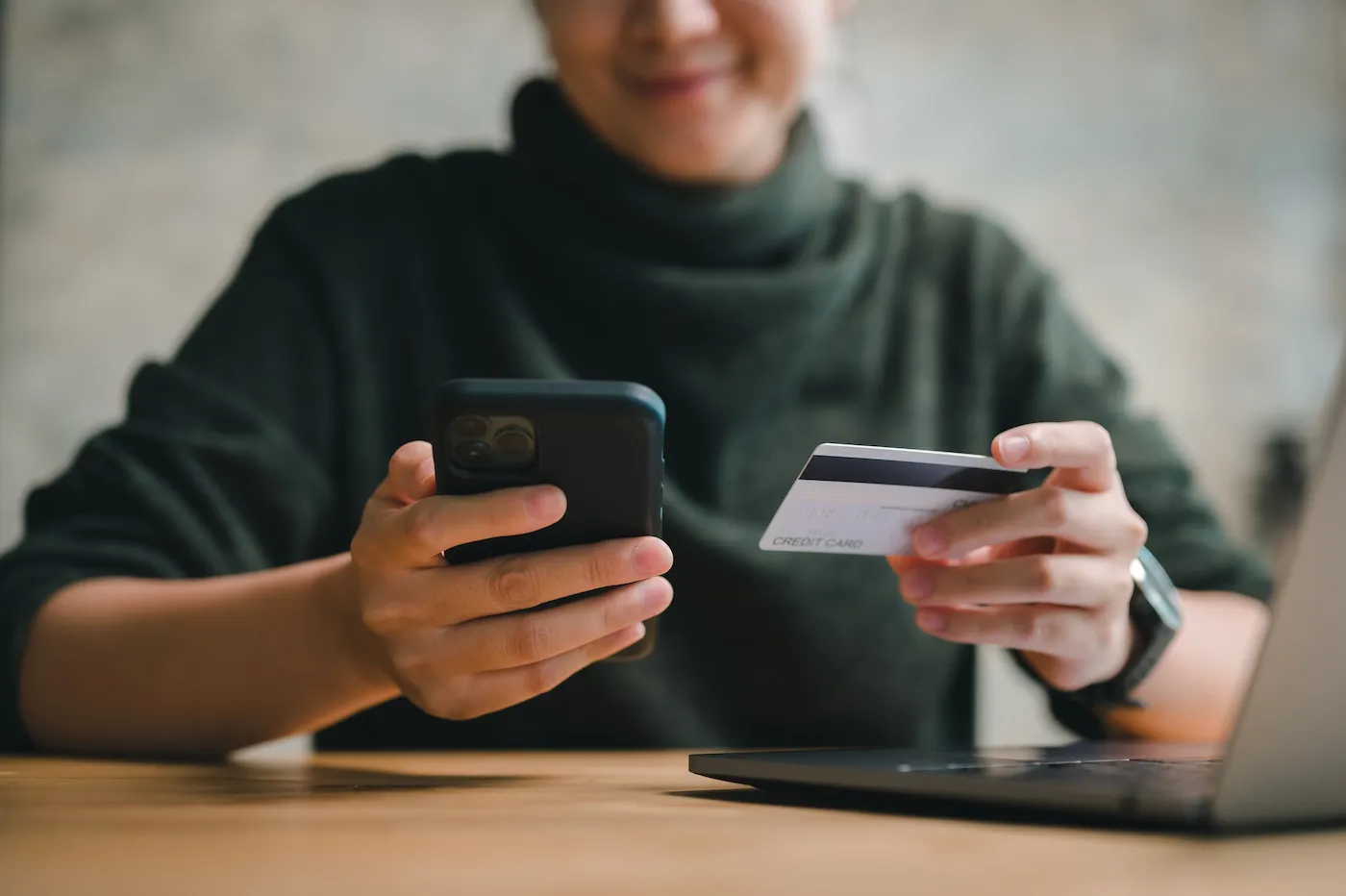 A person making a balance transfer using a credit card and their mobile phone.