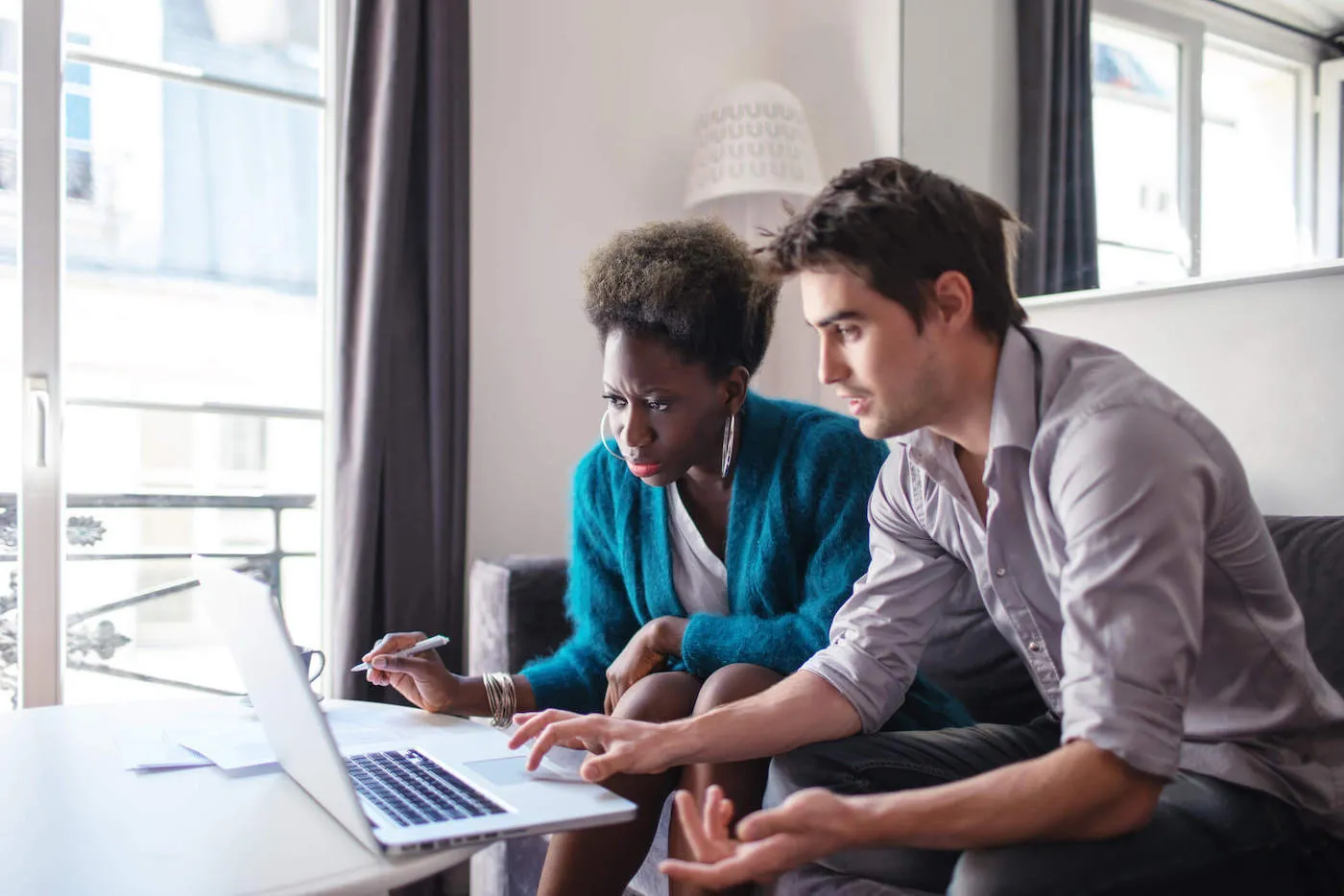 Man and woman seated next to each other looking at laptop screen.