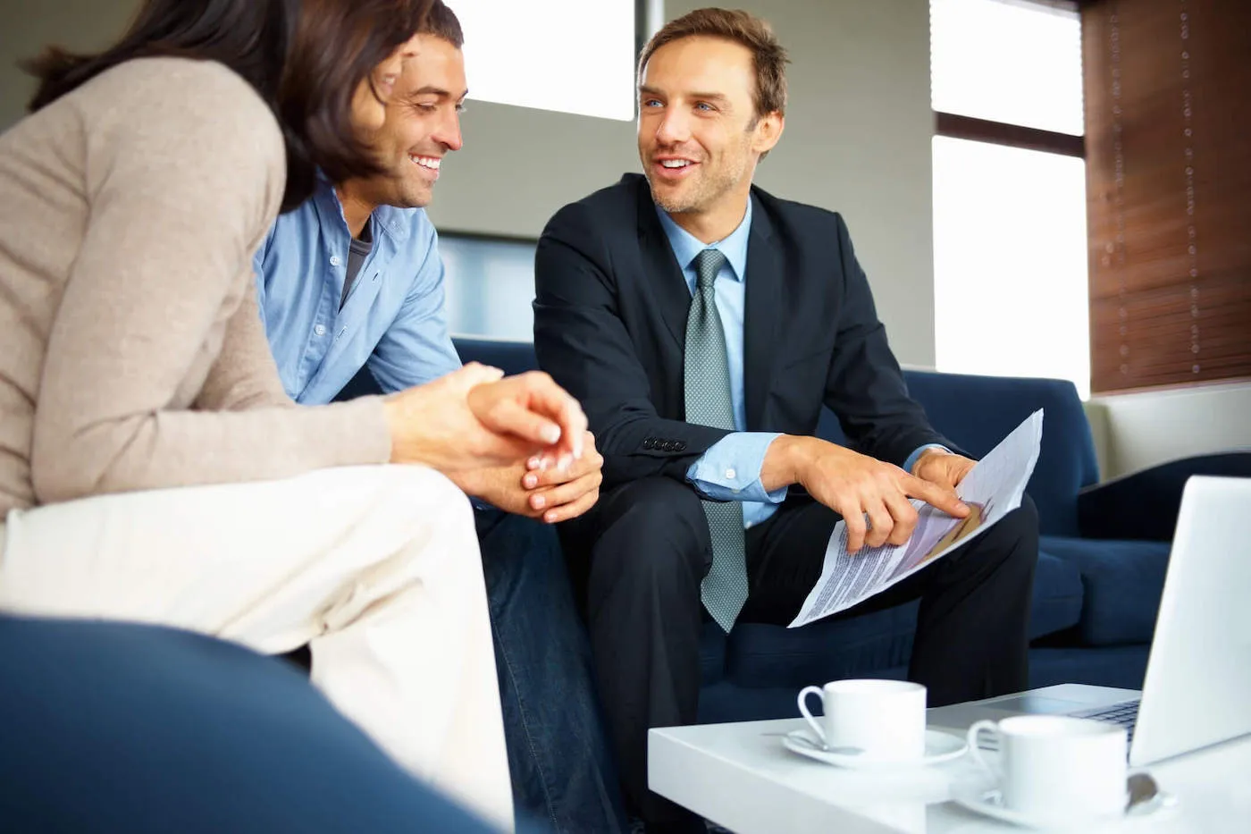 Man in suit explaining manual underwriting to man and woman couple.