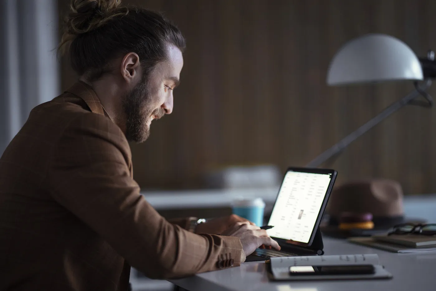 Young happy businessman sitting at the table typing on computer, researching the types of CDs