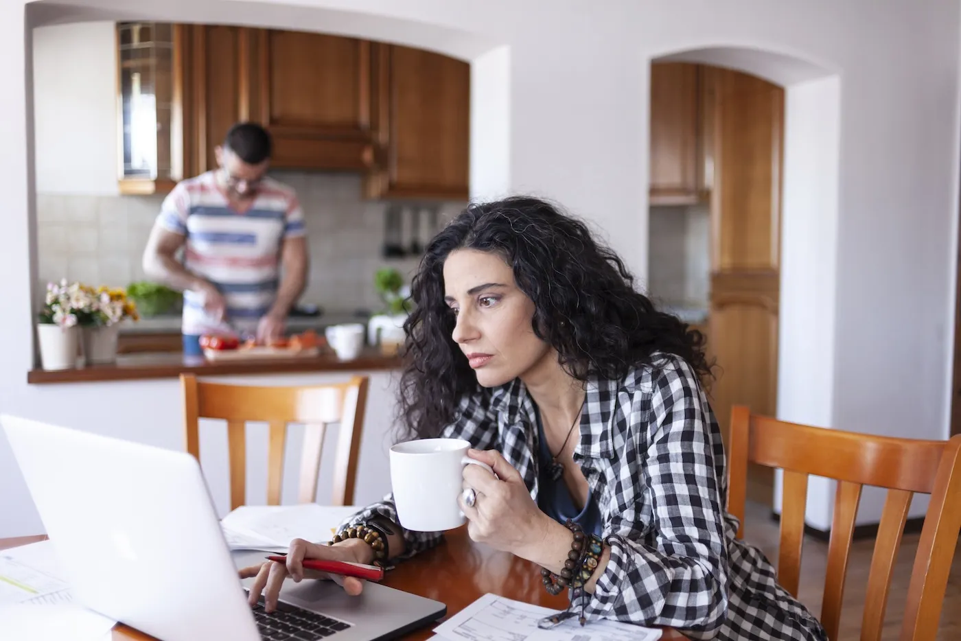 A woman looking at documents using her laptop at home.