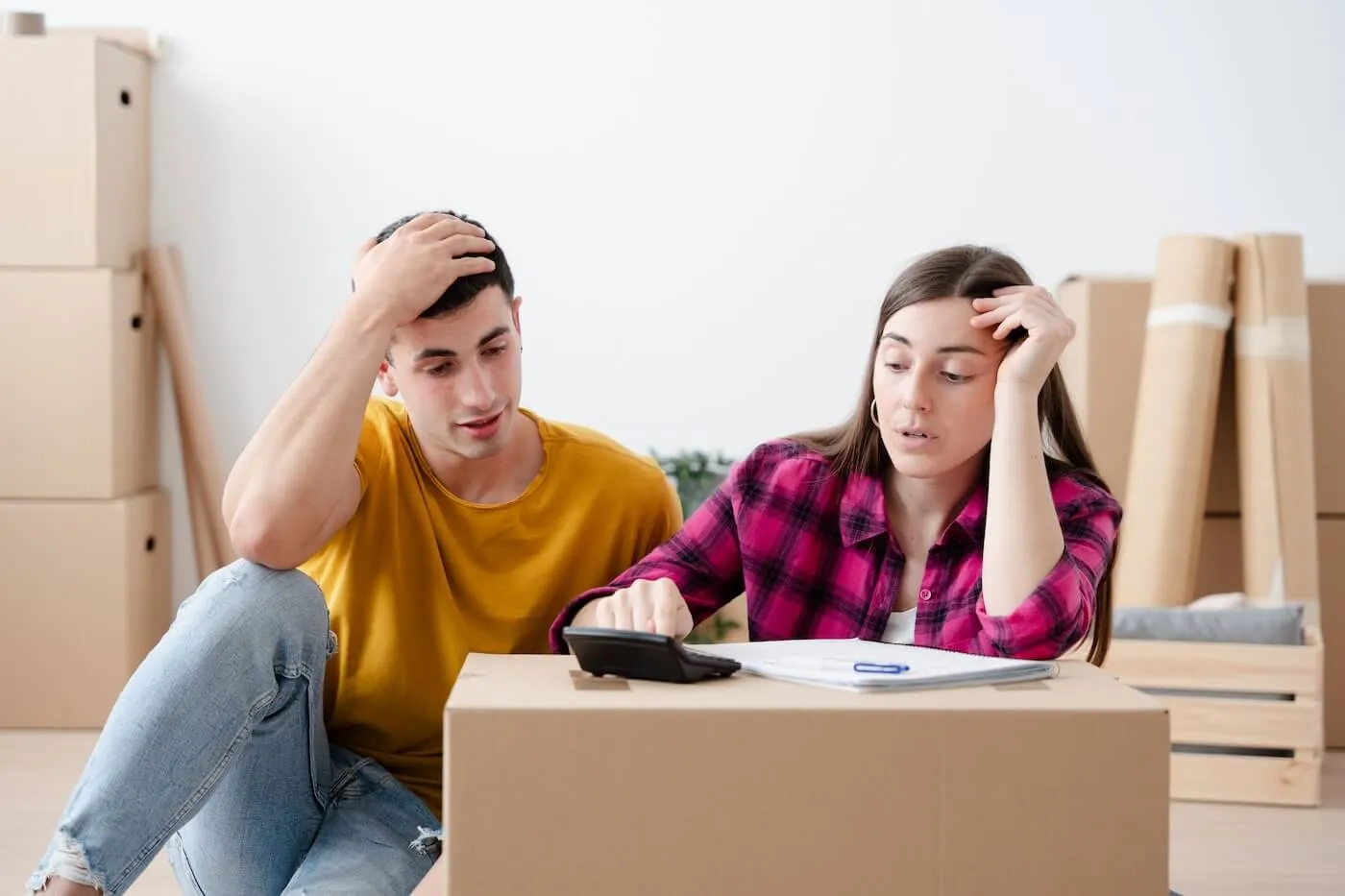 Concerned young couple calculating mortgage payment surrounded by boxes