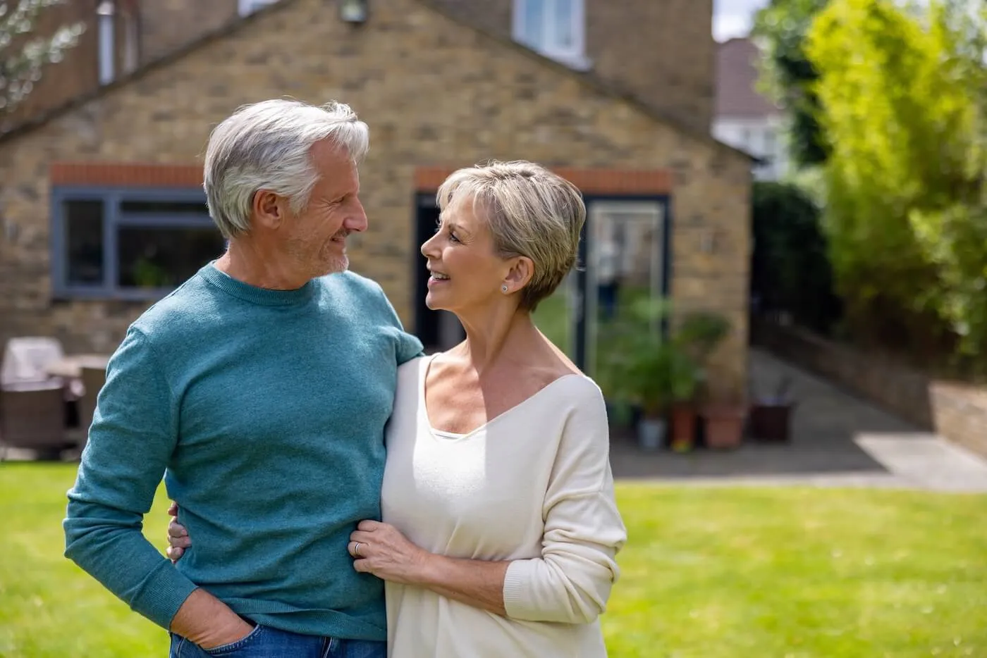 Senior couple hugging in front of their house