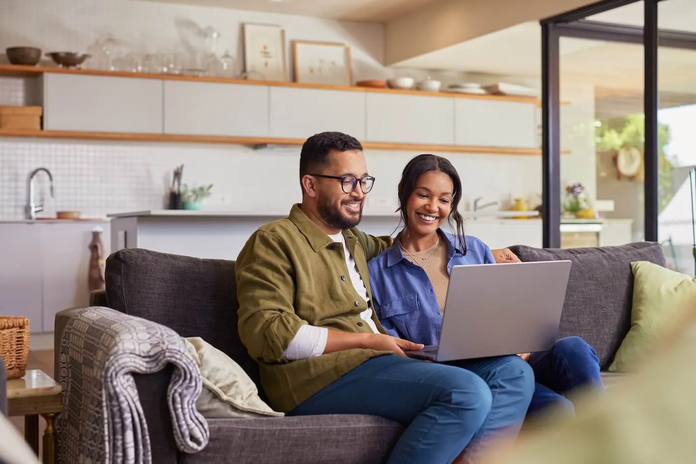 Happy young couple sitting comfortably on a couch with a laptop