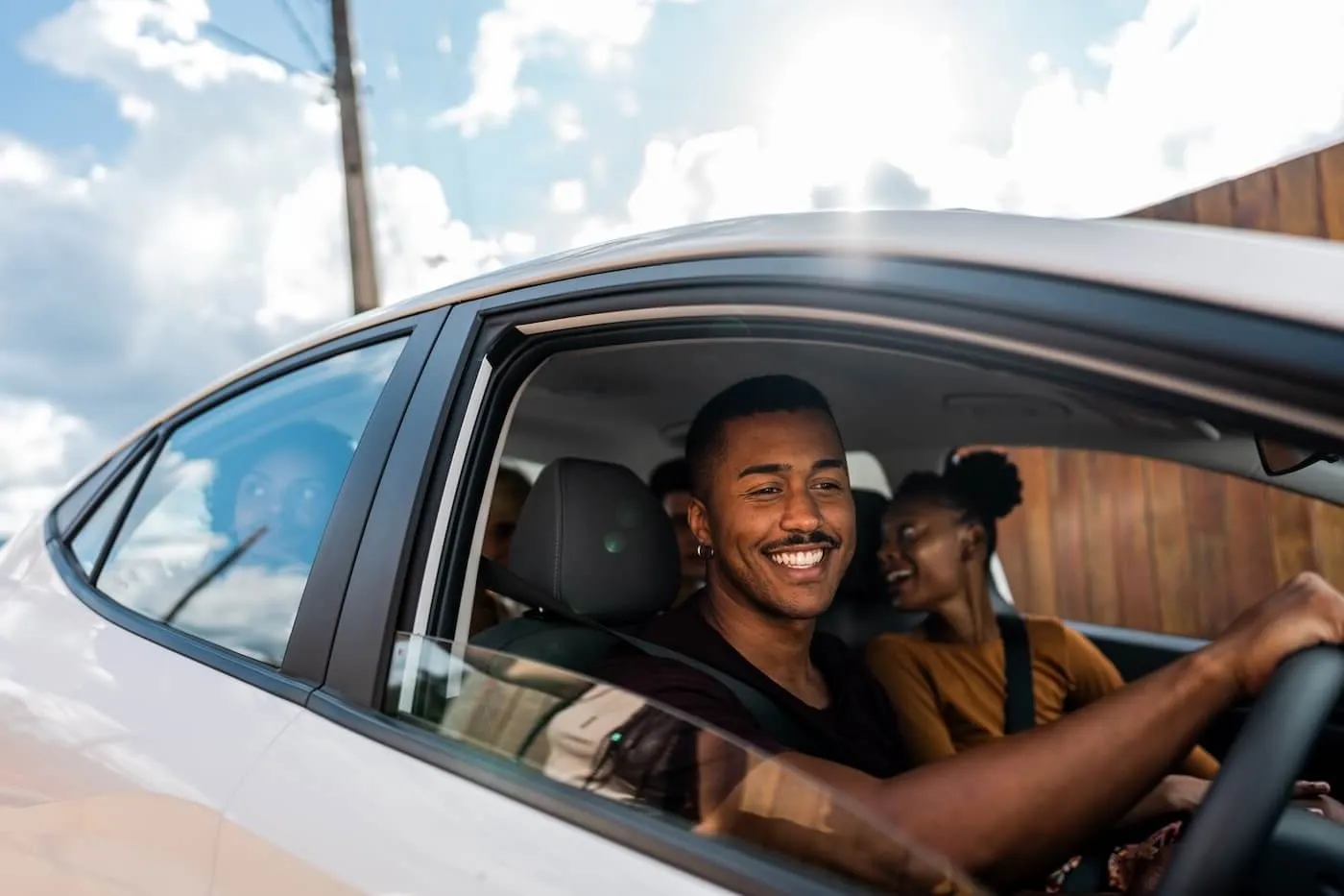 Smiling man driving a car with the passengers